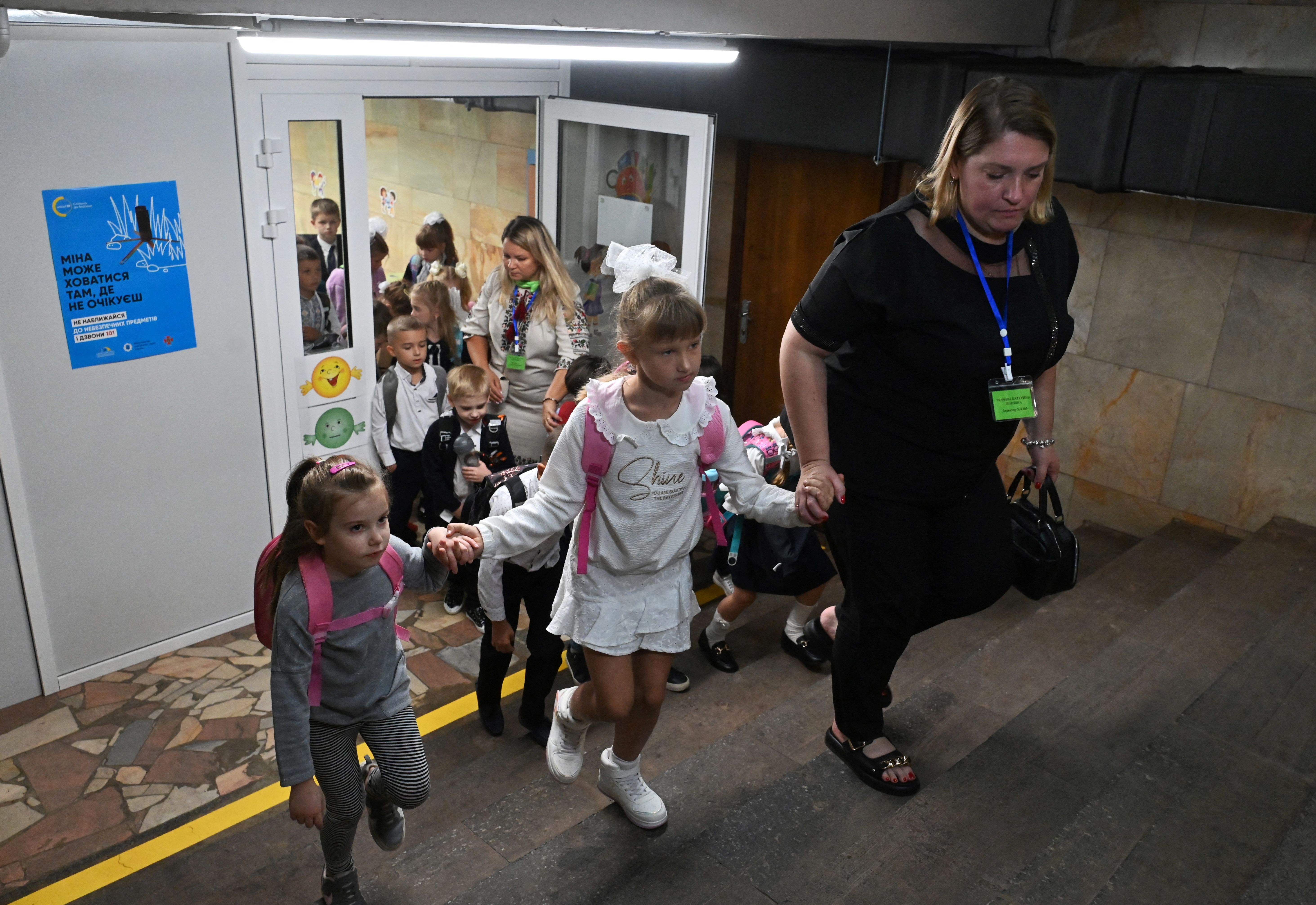 Alumnos de primer grado salen después de clases en un aula instalada en una estación de metro en Kharkiv, en medio de la invasión rusa de Ucrania. (Foto de SERGEY BOBOK/AFP vía Getty Images)
