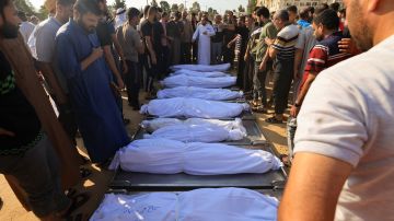 dolientes se reúnen alrededor de los cuerpos envueltos de miembros de la familia Agha, muertos en un ataque israelí en Khan Yunis, en la Franja de Gaza