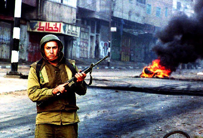 U soldado israelí patrulla mientras los enfrentamientos con jóvenes palestinos el 27 de noviembre de 1993.