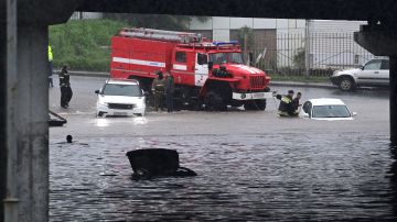 TOPSHOT - Rescuers try to pull a car from a flooded street after heavy rain in Vladivostok, on August 25, 2023. (Photo by Pavel KOROLYOV / AFP) (Photo by PAVEL KOROLYOV/AFP via Getty Images)