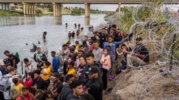 Los solicitantes de asilo esperan ser procesados ​​por agentes de la Patrulla Fronteriza de EE. UU. después de cruzar el Río Grande.