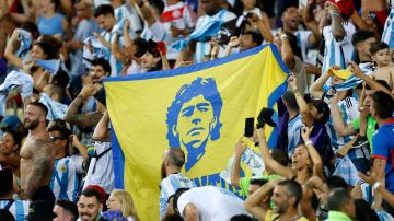 Hinchas de Argentina muestran una bandera con el retrato de Diego Armando Maradona.