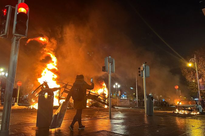 Las llamas se elevan desde el automóvil y el autobús, incendiados en el cruce de Bachelors Walk y el puente O'Connell, en Dublín, mientras la gente salía a las calles tras los apuñalamientos ocurridos horas antes. (Foto de PETER MURPHY/AFP vía Getty Images)