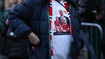 Un hincha viste una camiseta en honor a Sir Bobby Charlton.