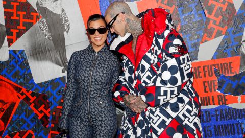 Kourtney Kardashian y Travis Barker posando en una alfombra roja.