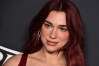 Dua Lipa posando en una alfombra roja.