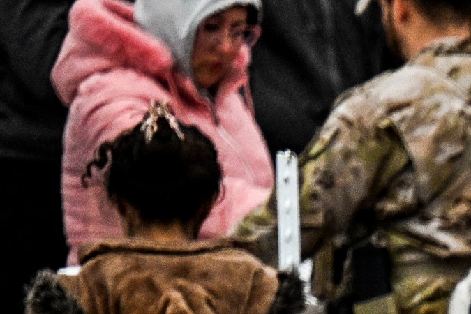 Un oficial de Aduanas y Protección Fronteriza de EE. UU. (C) da comida a inmigrantes que esperan ser procesados ​​en un centro de tránsito de la Patrulla Fronteriza.