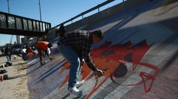 Activistas pintan un mural para denunciar la violencia de género y el maltrato a los migrantes junto al río Bravo en Ciudad Juárez.