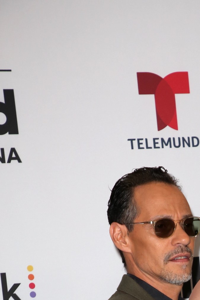 Marc Anthony y Nadia Ferreira posando en una alfombra roja.