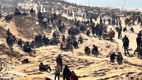 Palestinos esperan ayuda humanitaria en una playa de la ciudad de Gaza.