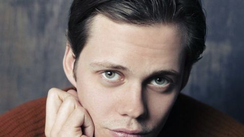 Bill Skarsgård posando en una alfombra roja.