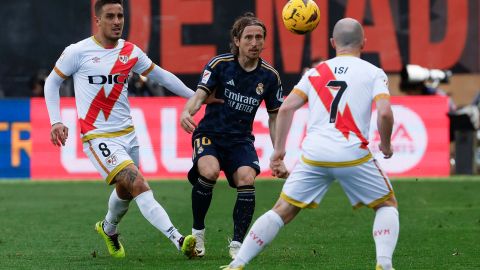 El centrocampista croata del Real Madrid Luka Modric (c) disputa el balón con el delantero Óscar Trejo (i) y el centrocampista Isi Palazón (d), jugadores del Rayo Vallecano.