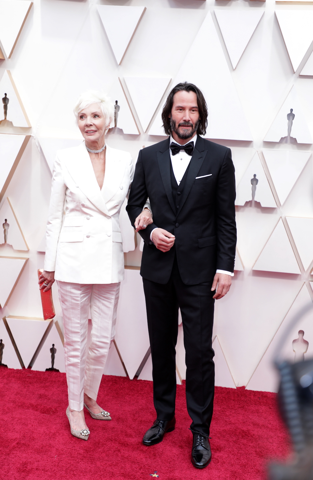 Keanu Reeves posando en una alfombra roja.