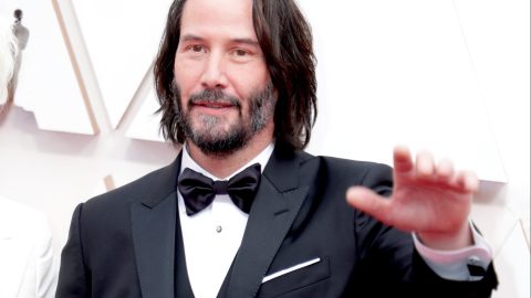 Keanu Reeves posando en una alfombra roja.