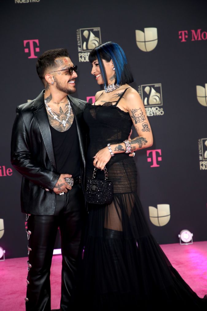 Christian Nodal y Cazzu posando en una alfombra roja.