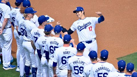 El lanzador de Los Dodgers, Shohei Ohtani (d), saluda a sus compañeros en su debut con el equipo al inicio del partido entre los Dodgers de Los Ángeles y los Cardenales de San Luis.