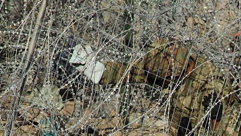 Personal de la Guardia Nacional estadounidense refuerzan una cerca de navajas y púas.