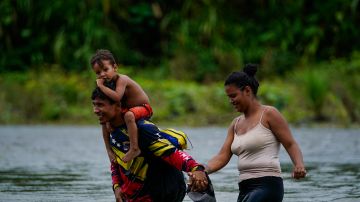 Migrantes venezolanos atraviesan un río en la selva del Darién.