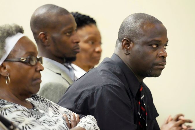 Eddie Terrell Parker, derecha, y Michael Corey Jenkins, centro, escuchan mientras uno de los seis exagentes de la ley de Mississippi se declara culpable de los cargos estatales.