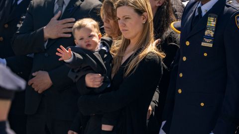 Jonathan Diller's wife Stephanie Diller and her son watch the casket during a funeral service for New York City Police Department officer Jonathan Diller at Saint Rose of Lima R.C Church in Massapequa Park, N.Y., on Saturday, March 30, 2024. Diller was shot dead Monday during a traffic stop. He was the first New York City police officer killed in the line of duty in two years.(AP Photo/Jeenah Moon)