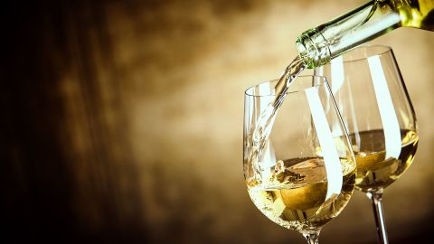 Pouring,Two,Glasses,Of,White,Wine,From,A,Bottle,In