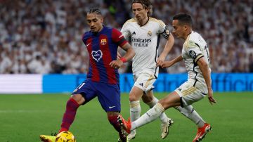 El defensa del Real Madrid Lucas Vázquez (dcha) y el centrocampista croata Luka Modric (c) pelean por el balón con el delantero brasileño del FC Barcelona Raphinha.