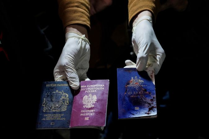 Un hombre muestra pasaportes británicos, polacos y australianos manchados de sangre después de un ataque aéreo israelí.