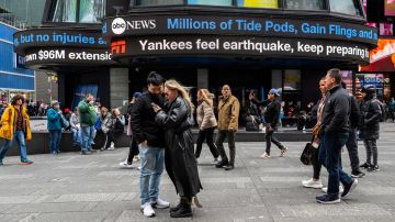 Personas recorren Times Square mientras las pantallas muestran noticias sobre el sismo del viernes 5 de abril en Nueva York. (AP Foto/Brittainy Newman)