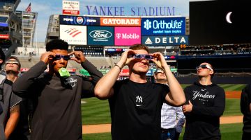 Juan Soto (L) y Clarke Schmidt (R) aprecian el eclipse solar desde el Yankee Stadium.