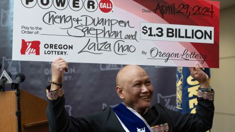 Saephan sostiene el cheque sobre su cabeza después de hablar durante una rueda de prensa donde se reveló que fue uno de los ganadores del premio mayor de Powerball.