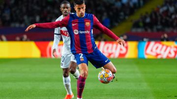 El defensa portugués del FC Barcelona João Cancelo (d) disputa un balón ante el delantero francés del PSG Ousmane Dembélé.