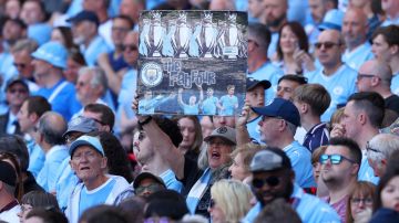 Un hincha del Manchester City sostiene un cartel para celebrar el cuarto título consecutivo de Premier League del equipo ciudadano.