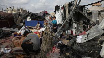 Palestinos desplazados inspeccionan sus tiendas de campaña destruidas por el bombardeo de Israel, adjuntas a una instalación de la UNRWA.