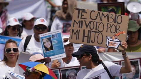 Una mujer sostiene un cartel con un mensaje que dice en español: "Cambiaré mi voto por mi hijo", en referencia a las elecciones presidenciales de este año.