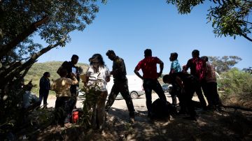 La Patrulla Fronteriza hablan con migrantes que buscan asilo mientras los preparan para el transporte para ser procesados.