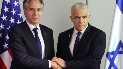 Antony Blinken le da la mano al líder de la oposición israelí, Yair Lapid, durante una reunión en Tel Aviv.