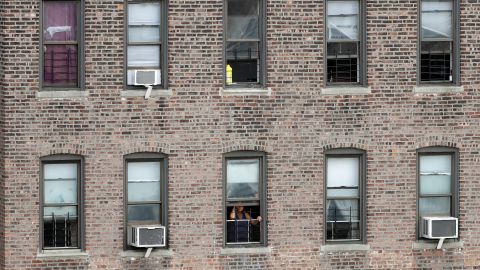A woman looks out from her apartment window on a hot summer day, Tuesday, July 11, 2017, in the Bronx borough of New York. (AP Photo/Mark Lennihan)
