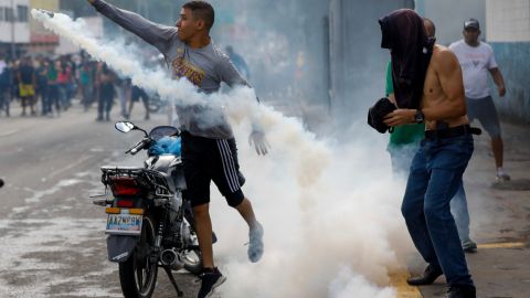 Un manifestante devuelve a la policía una bomba de gas lacrimógeno durante las manifestaciones contra los resultados electorales en Venezuela.
