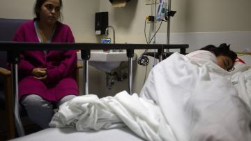 Tamara Carrasquillo  junto a su hija Anaia Salinas, de 9 años, hospitalizada por dengue en el Hospital Auxilio Mutuo, en San Juan, Puerto Rico.