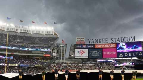 Equipo del Yankee Stadium coloca la lona sobre el terreno antes de la lluvia.