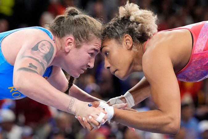 La estadounidense Kennedy Alexis Blades y la rumana Catalina Axente, vestidas de azul, compiten en los octavos de final de la lucha libre femenina de 76 kg en el Champ-de-Mars Arena durante los Juegos Olímpicos de París 2024, el sábado 10 de agosto de 2024, en París, Francia. (Foto AP/Eugene Hoshiko)