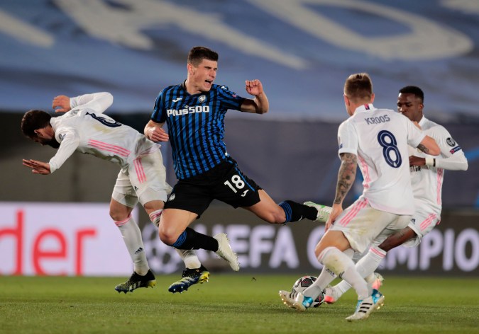 Ruslan Malinovskyi del Atalanta salta por el balón contra Nacho del Real Madrid durante el partido de vuelta de los octavos de final de la Liga de Campeones entre Atalanta y Real Madrid en el estadio Alfredo di Stefano en Madrid, España, el martes 16 de marzo de 2021. (Foto AP/Bernat Armangue)