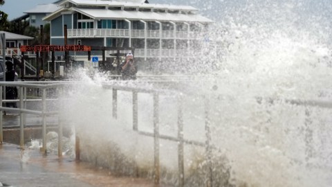 Un hombre toma fotografías de las olas impulsadas por los vientos de la tormenta tropical Debby mientras rompen sobre el malecón en Cedar Key, Florida, el domingo 4 de agosto de 2024.