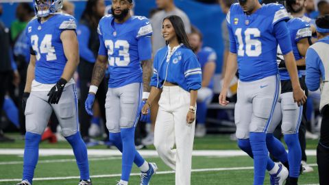 Diana Flores (C) camina con jugadores de Detroit Lions previo a su homenaje.