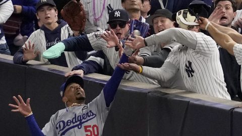 Fanáticos de los Yankees interfieren con la jugada del jardinero de Los Angeles Dodgers Mookie Betts.