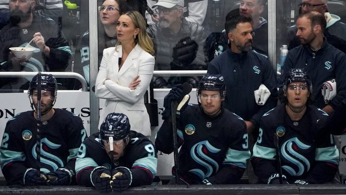 Entrenadora asistente de los Seattle Kraken, Jessica Campbell, vestida de blanco, observa desde el banquillo durante el primer período de un partido de hockey de la NHL contra los St. Louis Blues, el martes 8 de octubre de 2024, en Seattle.