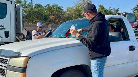 Migrantes venezolanos limpian el parabrisas de un carro, el 10 de octubre de 2024, en un avenida en Aurora (Estados Unidos).