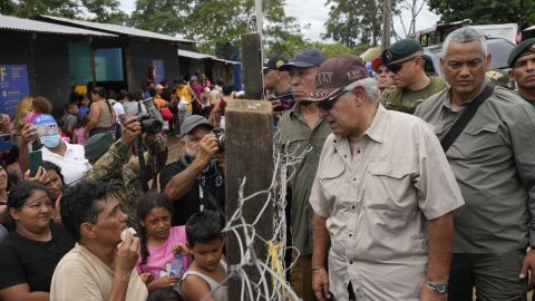 El ahora presidente de Panamá, José Raúl Mulino, habla con un migrante venezolano (izquierda) y otros migrantes en un campamento después de que cruzaron el Tapón del Darién desde Colombia, en Lajas Blancas, Panamá, el 28 de junio de 2024.