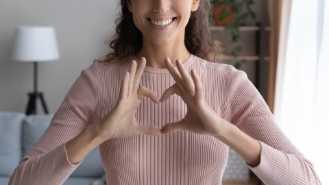 Close,Up,Cropped,Image,Smiling,Young,Woman,Showing,Heart,Love