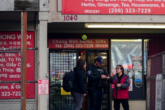 Los agentes de policía toman declaración al dueño de un negocio cercano después de que varias personas fueran apuñaladas.